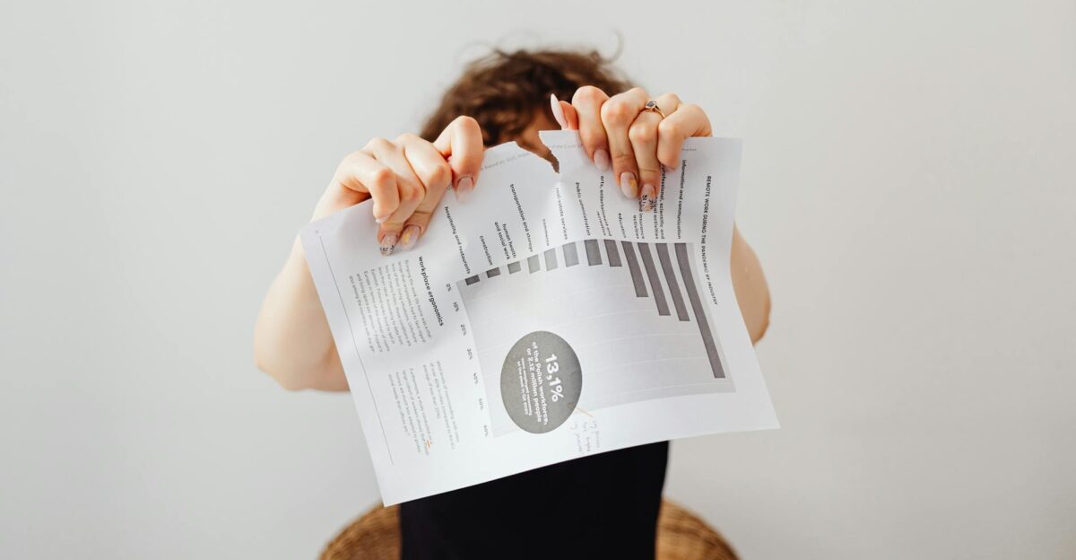 A frustrated individual tearing a printed document with graphs and text