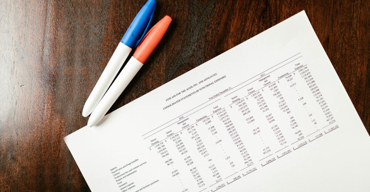A financial statement on a wooden desk with colorful pens ideal for accounting themes