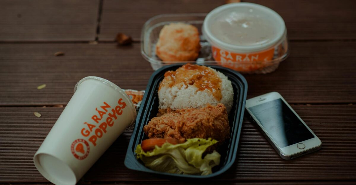 Delicious fried chicken meal from Popeyes with accompanying smartphone and drink on wooden table