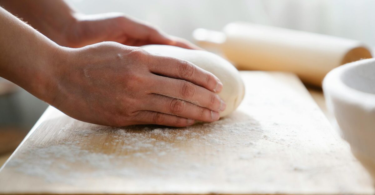 Close-up of hands kneading dough on a floured wooden board perfect for baking themes