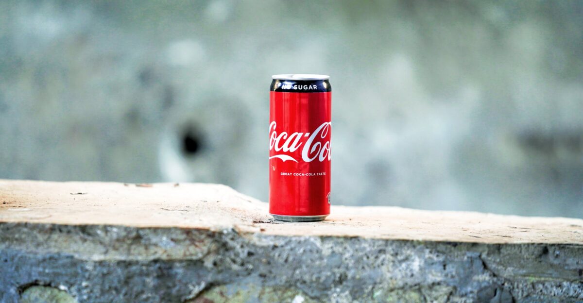 A can of Coca Cola placed on a rough concrete surface with a blurred background