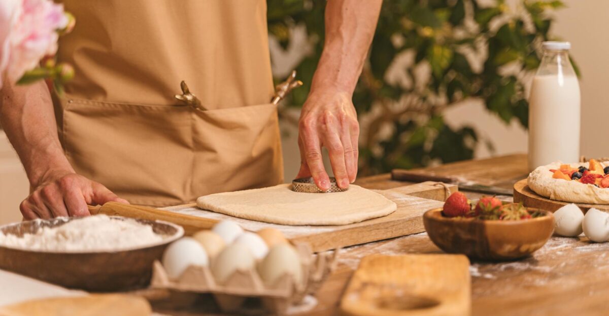 A person preparing homemade pastry dough with fresh ingredients in a warm kitchen setting