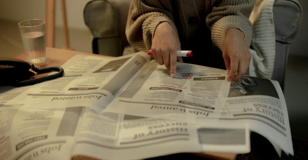 Close-up of a woman reading job listings in a newspaper highlighting employment search