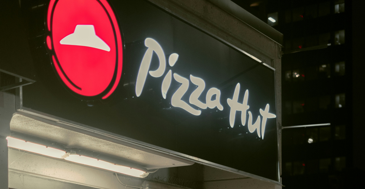 a man riding a bike past a pizza hut