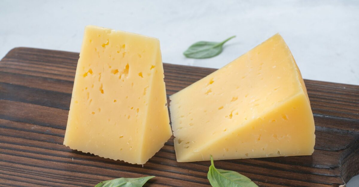 a couple of pieces of cheese sitting on top of a wooden cutting board