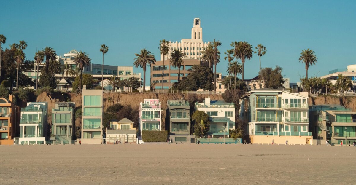 a row of houses on a beach with palm trees in the background