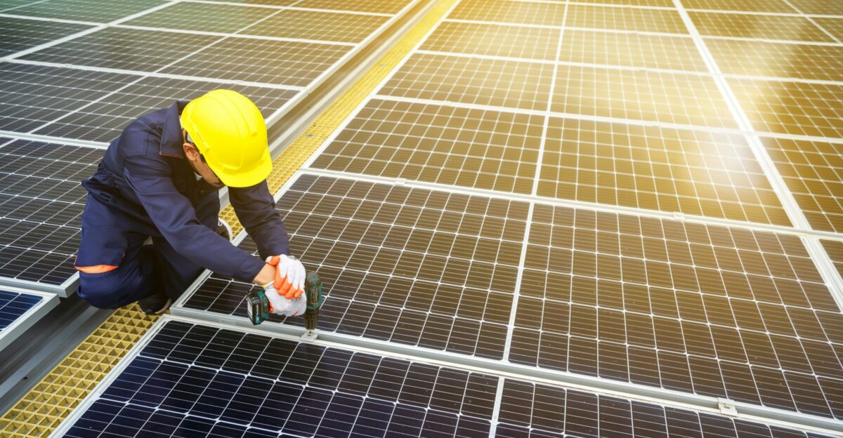 A man in a hardhat working on a solar panel