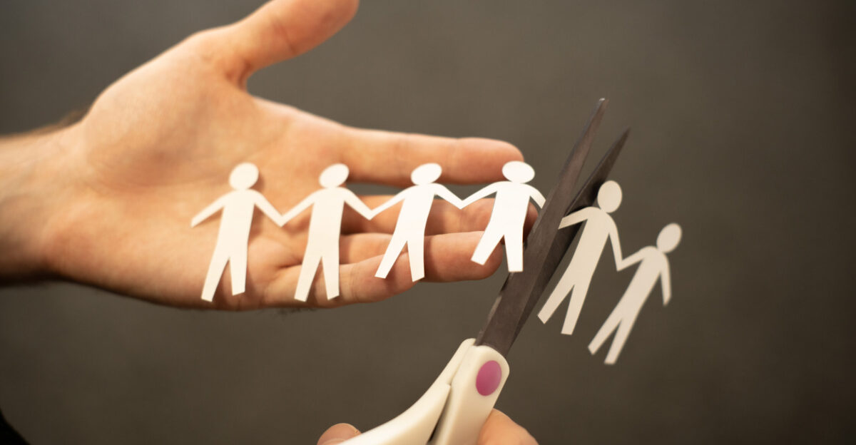 Photo of a person cutting a paper chain of figurines in half representing the concept of cutting jobs through redundancy This is an image available for you to use under the Attribution Creative Commons licence though we do ask that you credit ciphr com if you use it