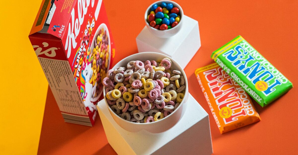 A vibrant flat lay of colorful breakfast cereals chocolate bars and candy on a geometric setup